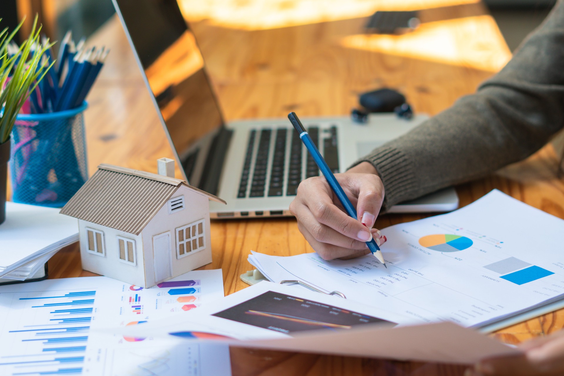 Modelli di case, magnati immobiliari stanno analizzando i guadagni attraverso grafici di analisi dei dati.